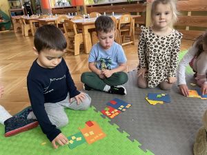 Dzieci układa kwadratowe kartoniki i papierowych prostokątach