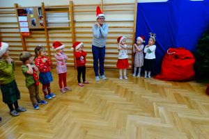 Dzieci z grupy 1 stoją w półkolu i śpiewają piosenkę mikołajowi 
