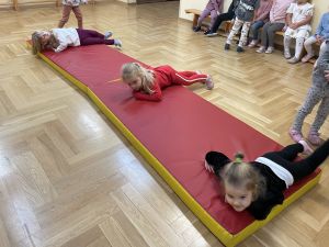 Dzieci turlają się na materacach w sali gimnastycznej