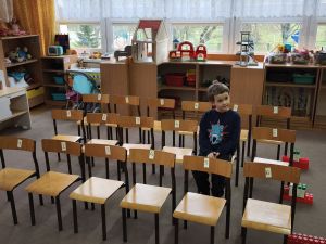 Chłopiec siedzi na krześle. Krzesełka ustawione są w 3 rzędach
