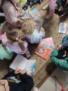 Dzieci siedzą na dywanie i oglądają książki