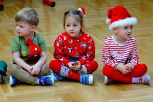 Dzieci siedzą na podłodze ubrane w świąteczne stroje