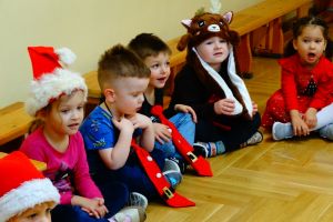 Dzieci siedzą na podłodze ubrane w świąteczne stroje