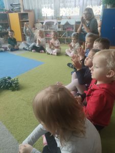 Dzieci siedzą w kole i patrzą na warzywa