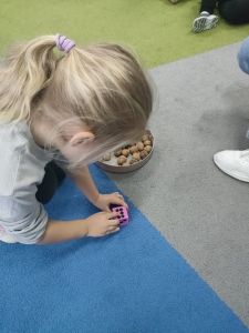 Dziewczynka siedzi na dywanie i liczy kropki na kostce