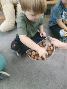 Chłopiec wybiera orzechy z pojemniczka.