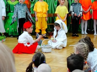 Dziewczynki w stroju czerwonego kapturka i w stroju zajączka siedzą na środku sceny 