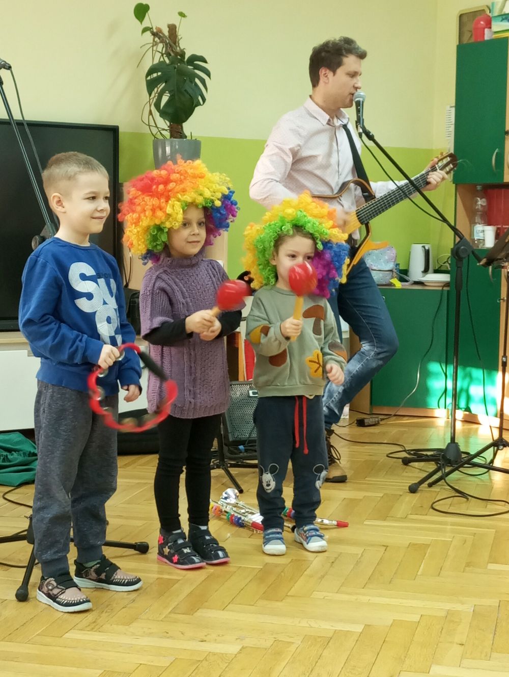 Pan gra na gitarze a 3 chłopców gra na grzechotkach i tamburynie