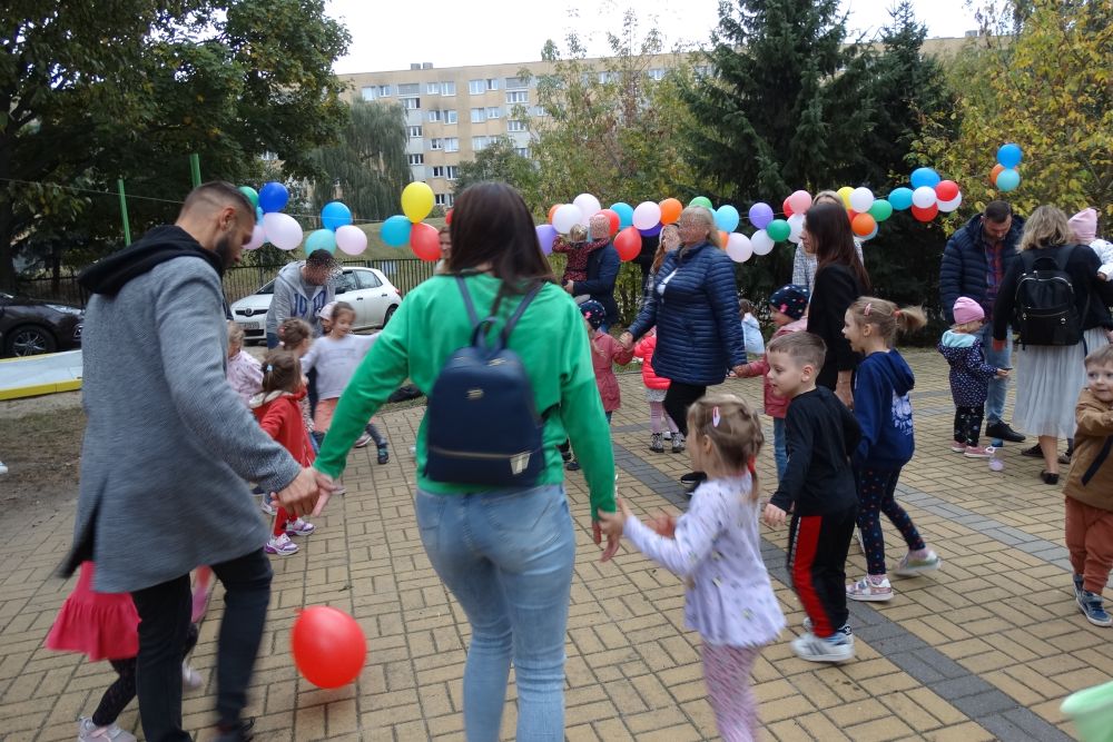 Rodzice i dzieci tańczą podczas pikniku na placu zabaw