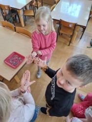 3 dzieci pokazuje jak do rąk przyczepia się konfetti