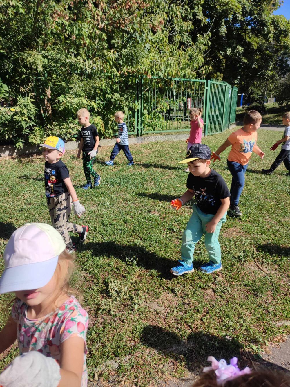 Dzieci chodzą po trawie i zbierają śmieci