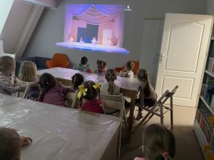 Dzieci siedzą na krzesłach i oglądają film o balecie