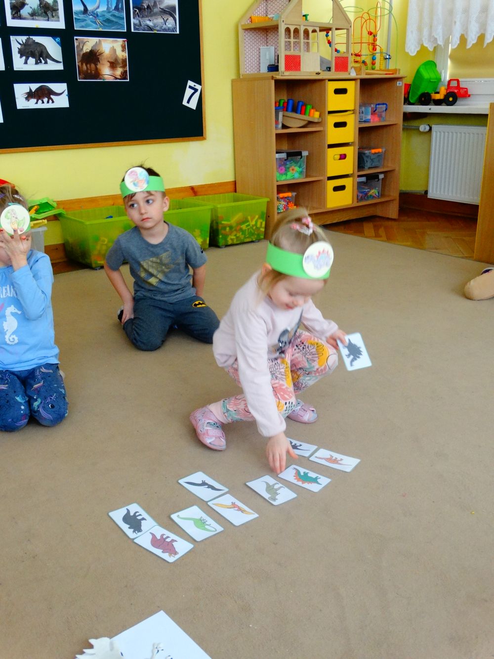 Dziewczynka dopasowuje cień do obrazka z dinozaurem
