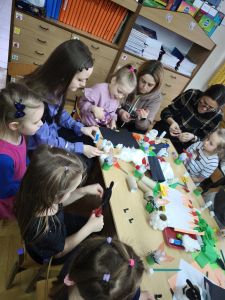 Rodzice z dziećmi wykonują wielkanocne ozdoby