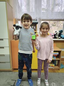 Chłopiec i dziewczynka pokazują zrobione prace- baranka i zajączka