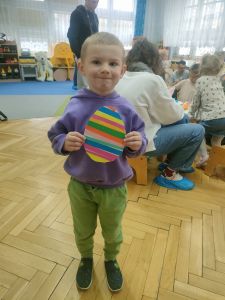 Chłopiec trzyma w rękach zrobione przez siebie jajko z papieru