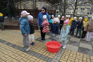 Dzieci stoją na przedszkolnym placu, Pani Ewa trzyma Marzannę