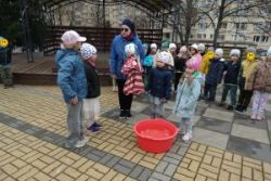 Dzieci stoją na przedszkolnym placu, Pani Ewa trzyma Marzannę