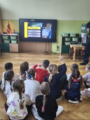 Dzieci siedzą na podłodze i oglądają film edukacyjny ze spongeBob.