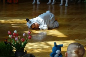 Chłopiec w stroju baranka leży na podłodze, udając że śpi